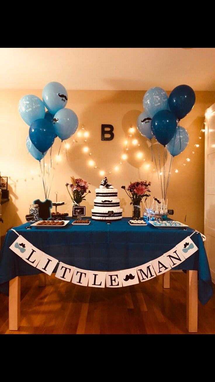 a table with blue balloons and a cake on it for a little man birthday party