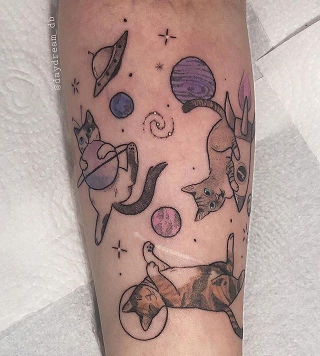 a tattoo with cats and planets on it's arm, as well as an image of the moon