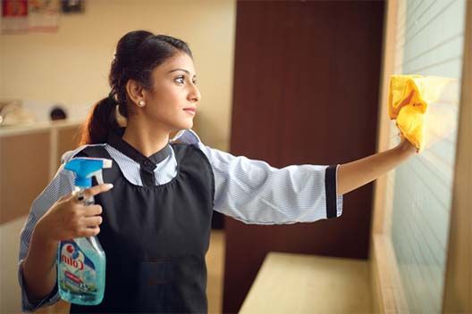 a woman is cleaning the wall with a sponge and detergent on her hand while holding a spray bottle