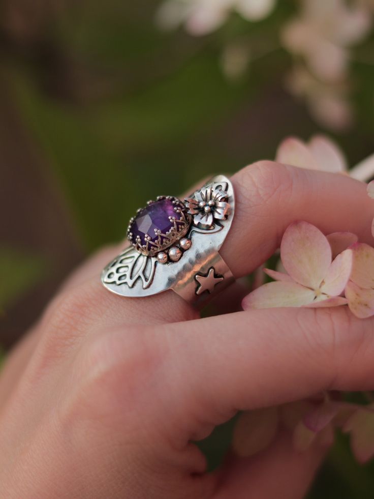 This magical shield ring was designed to protect you from evil and make you feel confident and happy in your skin. Entirely handcrafted in sterling silver, this ring features a lovely faceted amethyst gemstone and handmade embellishments. Size 6.5, but due to its wide band, the ring will comfortably fit size 6. You can see how this ring was made in this video: ➥ All Stardust Mine products are made by hand of a real person and not machine, using precious and semi-precious metals and natural stone Bohemian Sterling Silver Jewelry With Accent Stones, Mystical Sterling Silver Nickel-free Rings, Nickel Free Mystical Sterling Silver Ring, Nickel-free Mystical Sterling Silver Rings, Mystical Nickel-free Sterling Silver Rings, Spiritual Silver Amethyst Ring In Sterling Silver, Unique Crystal Open Ring With Gemstone Accents, Unique Sterling Silver Gemstone Flower Ring, Unique Adjustable Amethyst Promise Ring