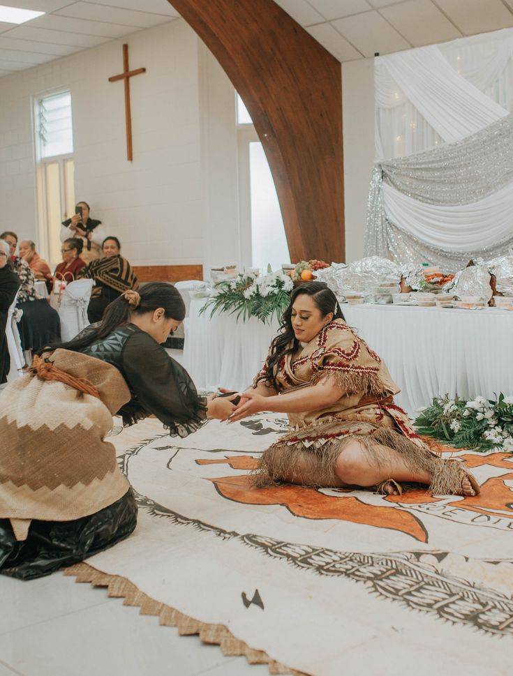 two people sitting on the floor in front of a group of people standing and sitting down