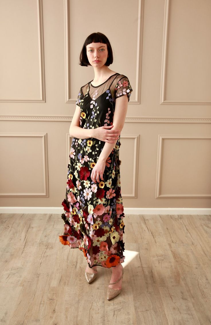 a woman in a floral dress standing on a wooden floor