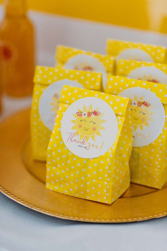 small yellow boxes with sun designs on them sitting on a gold plate next to honey jars