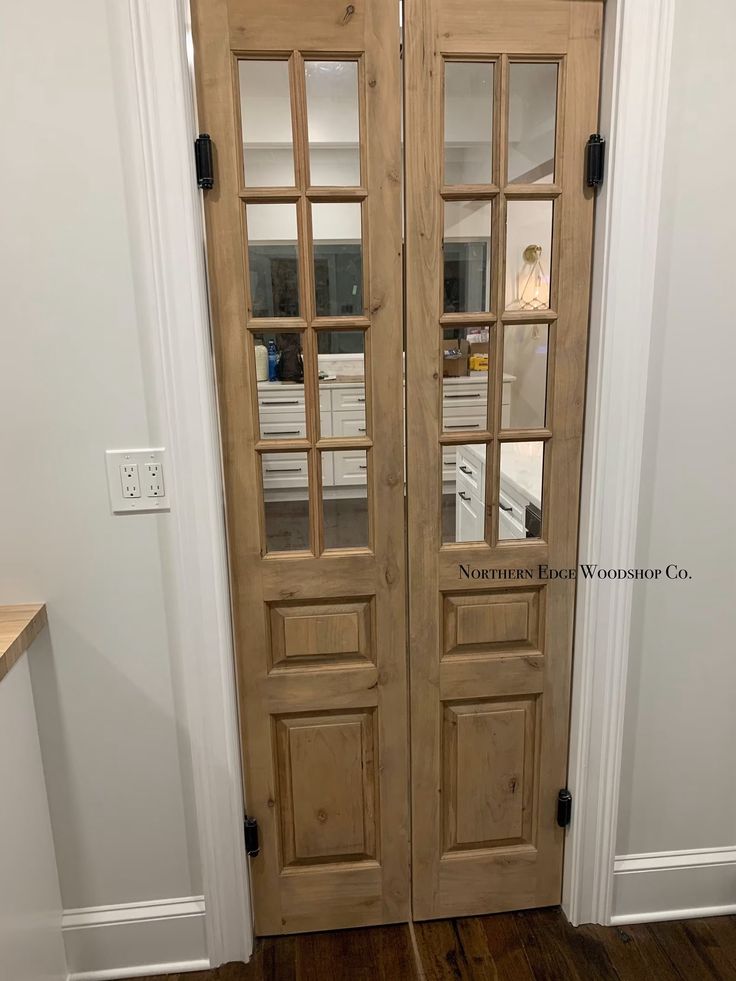 two wooden doors with glass panels in a home entryway, next to a hardwood floor