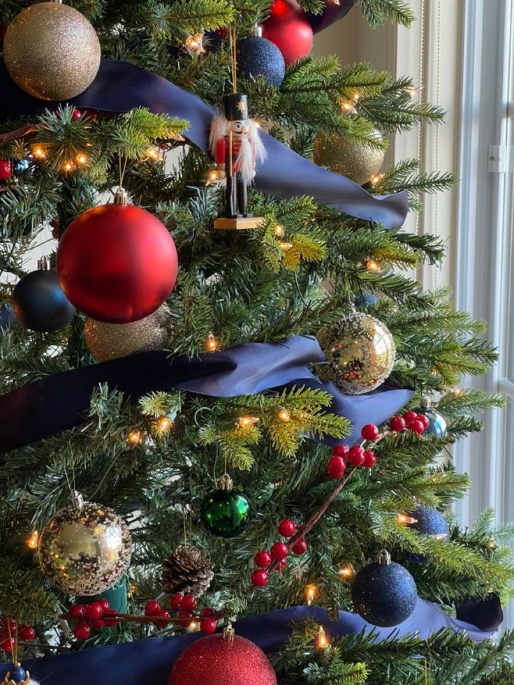 a christmas tree decorated with ornaments and ribbons in blue, red and gold colors is shown