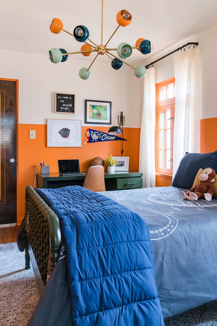 a bedroom with an orange accent wall and blue bedspread on the bottom bed