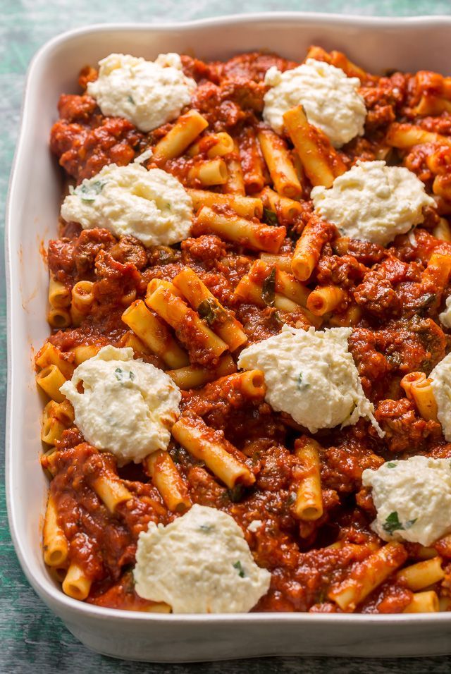 a casserole dish filled with pasta, cheese and sauce on a green table