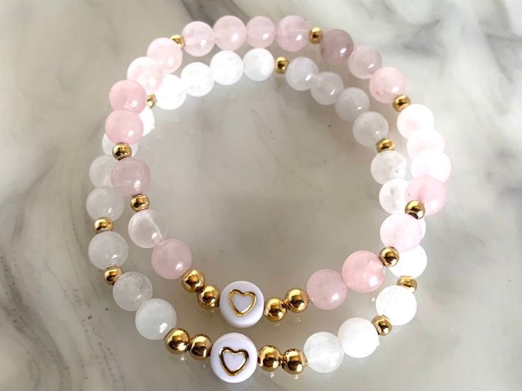 "This listing is for our beautiful White Jade or Pink Quartz and Gold Filled Bracelets.   6mm Smooth Round Beads enclosed on a double strand of elastic stretch cord with a white and gold heart bead.  *We've placed our smallest gold filled balls throughout and surrounding the heart.  Our gold filled beads are tarnish resistant :)  PLEASE READ BELOW   The standard size for all of our bracelets is 6.75 inches.  You can request custom sizes in the personalization box.  Be sure to reference the chart posted in the last photo if you are unsure of your size, but know it may not be a perfect fit unless you provide exact measurements.   Please take the extra step and measure your wrists and add 0.5\" to this measurement.  Our bracelets are made with double strand stretch cord and have some give but 8mm Beaded Bracelets Ideas, Beats Braslate, White Stretch Bracelet With Heart Beads For Birthday, Pink Beaded Name Bracelet As Gift, Pink Beaded Stretch Bracelet For Birthday, Pink Stretch Bracelet With Letter Beads For Gift, Cute Pink Stretch Bracelet With Custom Name, Wwjd Bracelet, Beautiful Beaded Bracelet