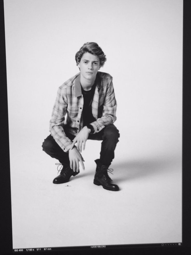 a young man is posing for a black and white photo with his hands on his knees