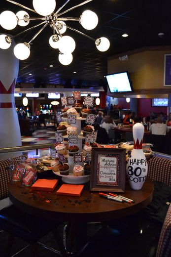 a table with some food on top of it in front of a tv screen and people sitting at tables