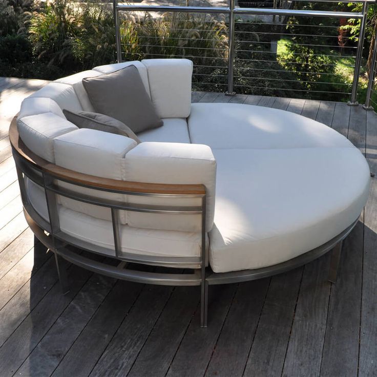 a white couch sitting on top of a wooden floor next to a metal rail fence