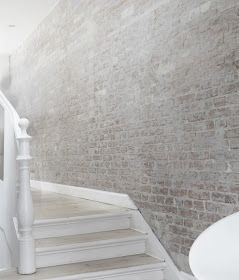 a white toilet sitting next to a brick wall on top of a stair case in a bathroom