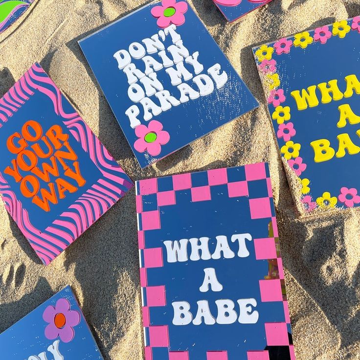 some pink and blue signs on the sand with words that read don't rain park parade what a babe