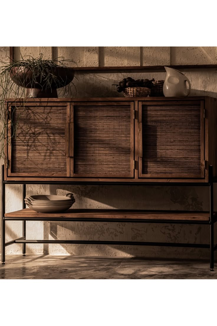 a wooden cabinet sitting on top of a table next to a vase and potted plant