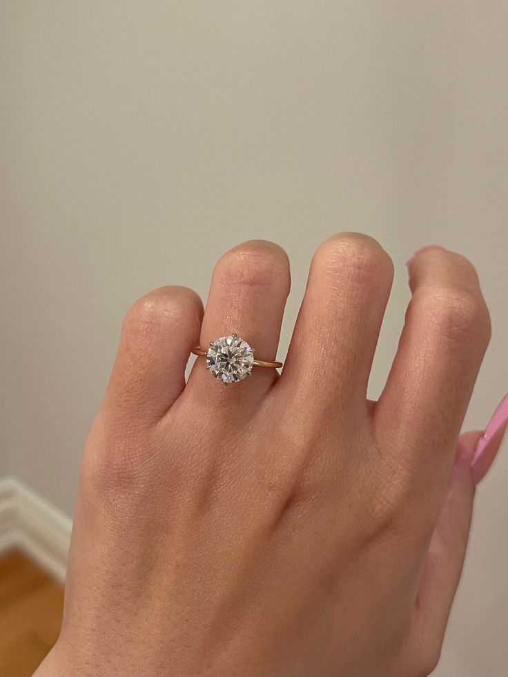 a woman's hand with a diamond ring on her left hand and a pink nail