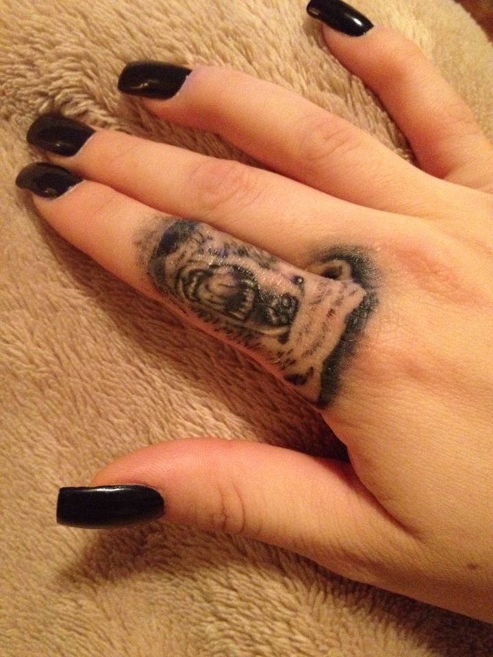 a woman's hand with black nails and a tattoo on her left thumb, holding onto a teddy bear