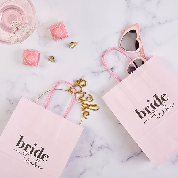 two pink bags that say bride and one with sunglasses on them sitting next to other items