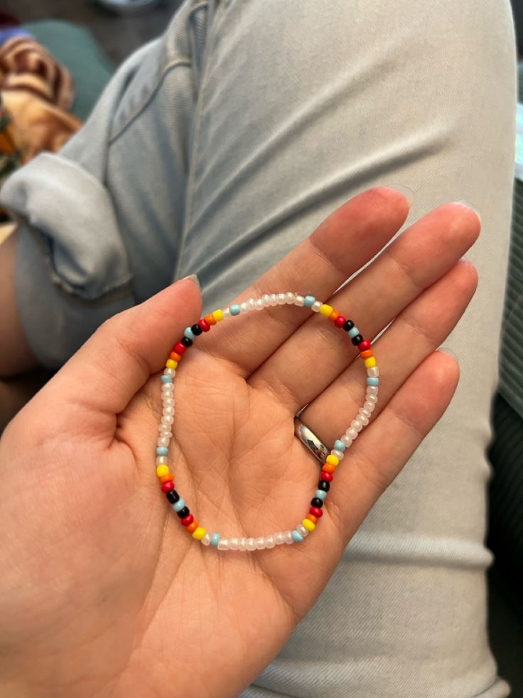 a person holding a beaded bracelet in their hand