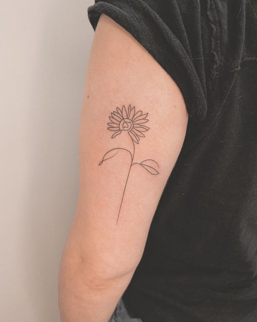 a woman's arm with a single line drawing of a sunflower on it