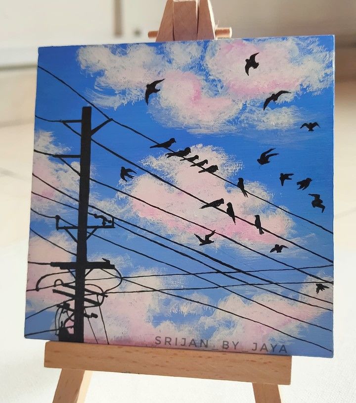 there is a painting on an easel that has birds flying over power lines in the sky