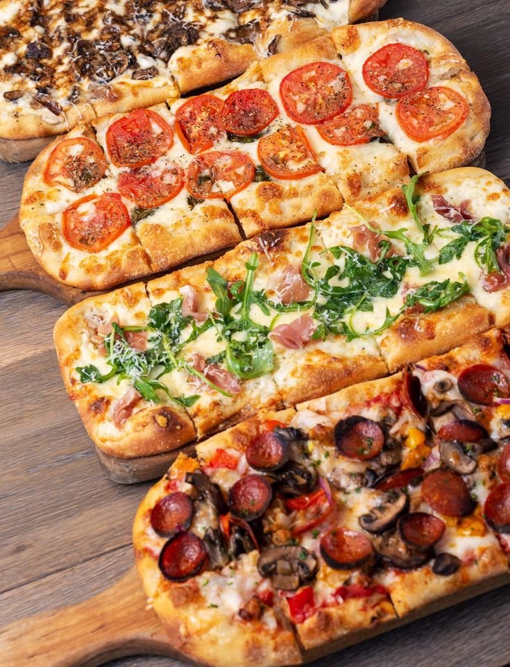 four different types of pizza on wooden cutting boards