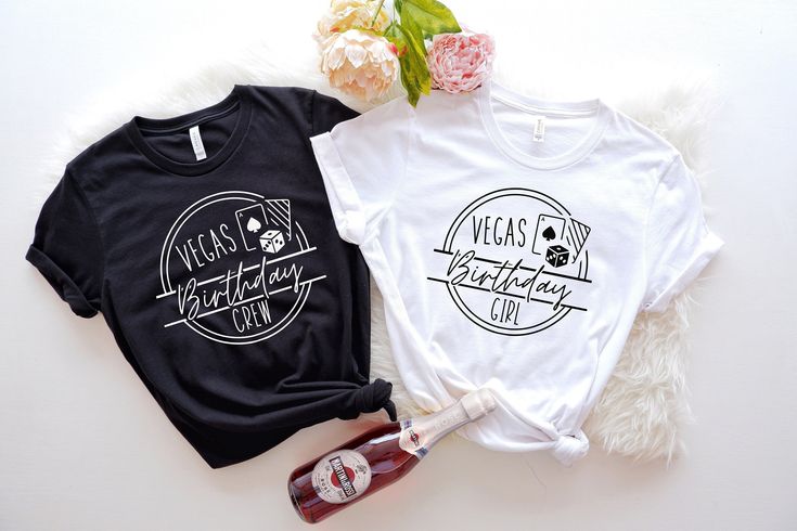 two t - shirts sitting next to each other on top of a white table with flowers