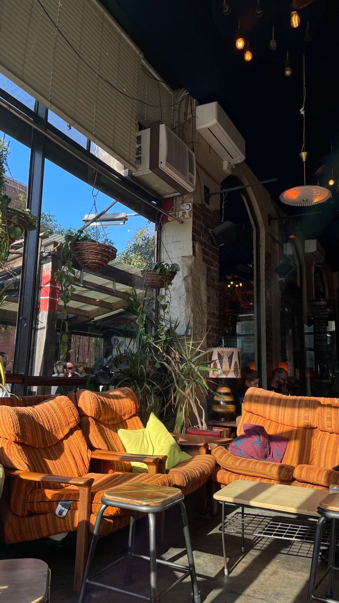 an outdoor seating area with chairs and tables in front of a large window that looks out onto the street