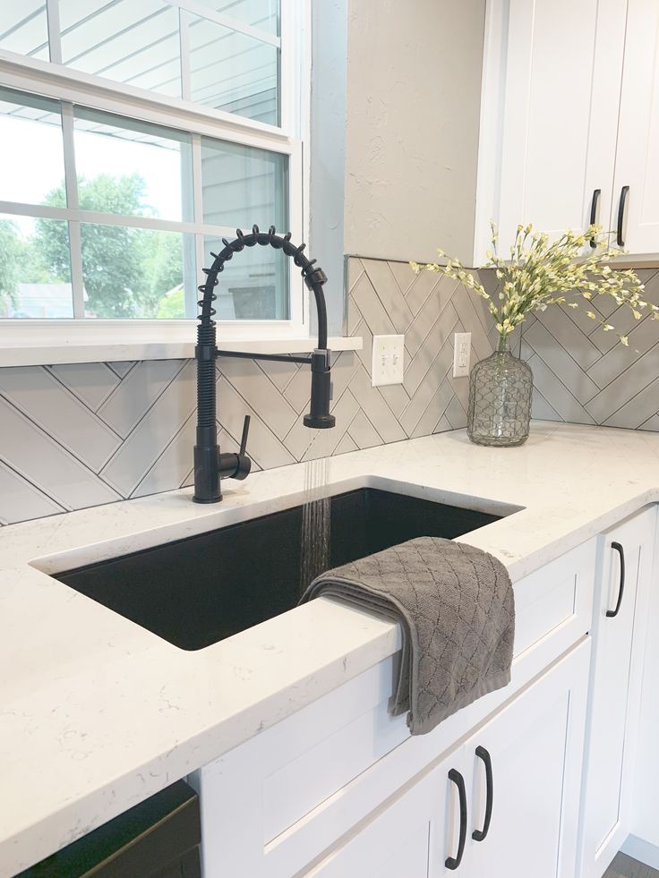 a kitchen sink with a black faucet and white cabinets