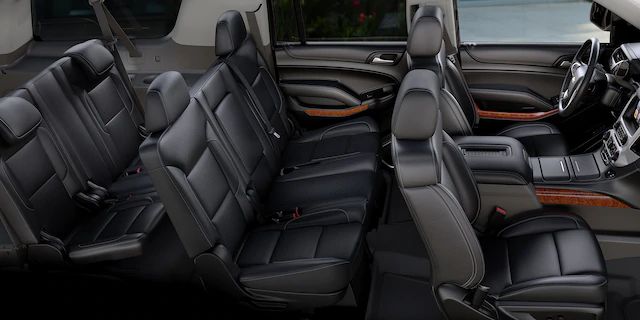 the interior of a vehicle with black leather seats and wood trim on the front row