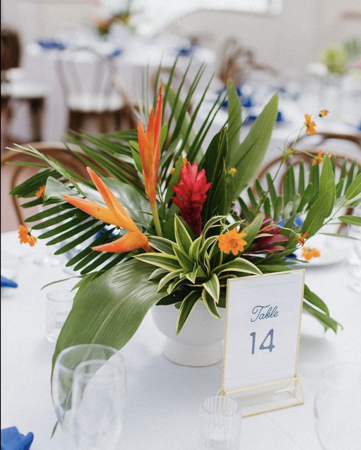 the table is set with tropical flowers and place cards for guests to sit down at