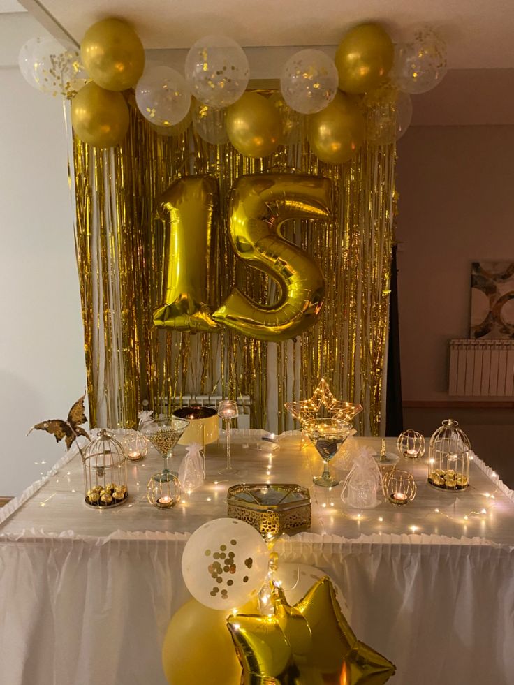 the table is set up with gold balloons and streamers for an elegant 21st birthday party