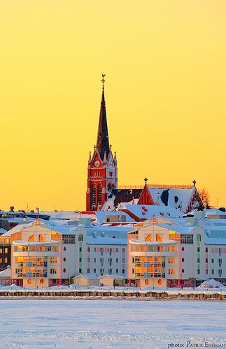 a large building with a clock tower in the middle of it's roof and snow on the ground