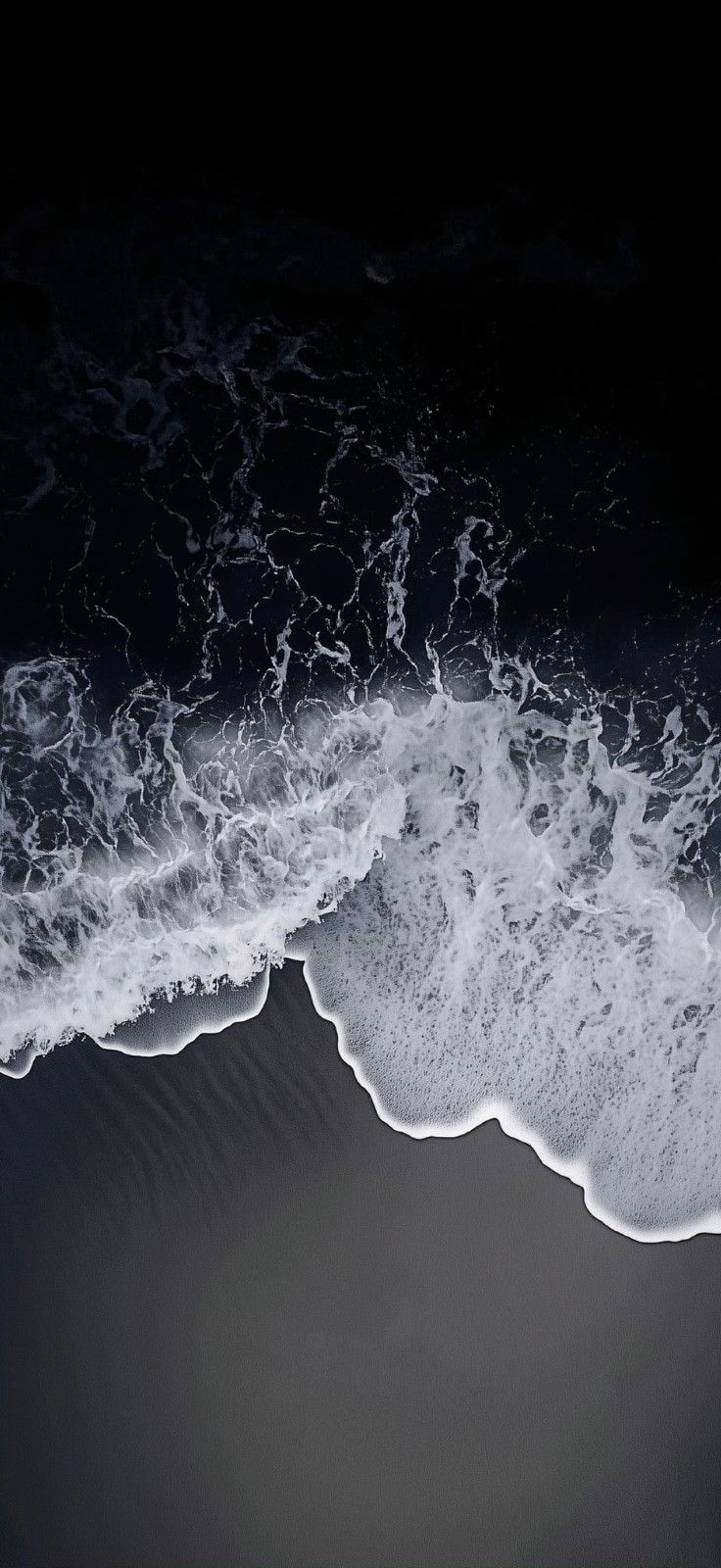 an aerial view of the ocean with waves coming in from the shore and dark background