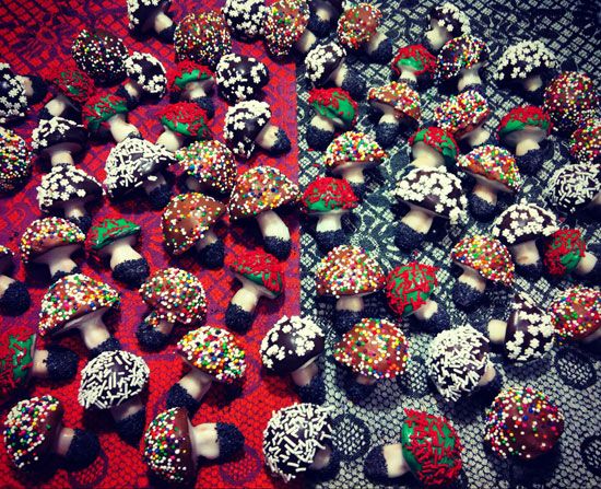 a table topped with lots of chocolate covered strawberries next to candy caned candies