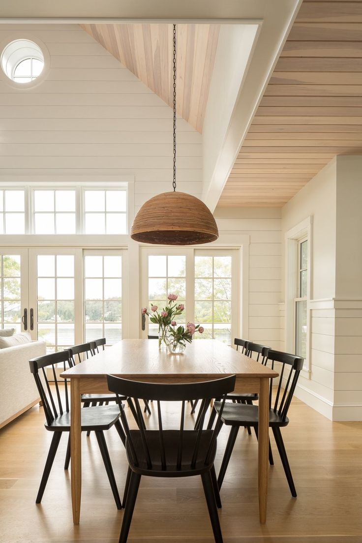 the dining room table is surrounded by black chairs and an oval light fixture hanging from the ceiling