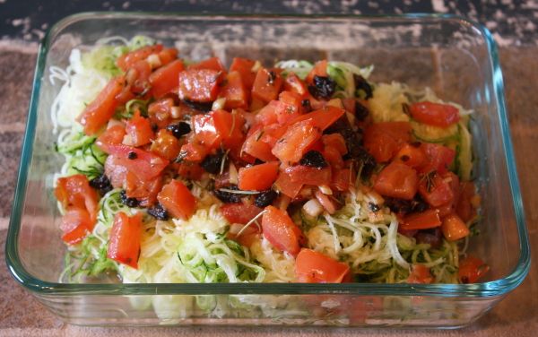 a glass dish filled with vegetables on top of a wooden table