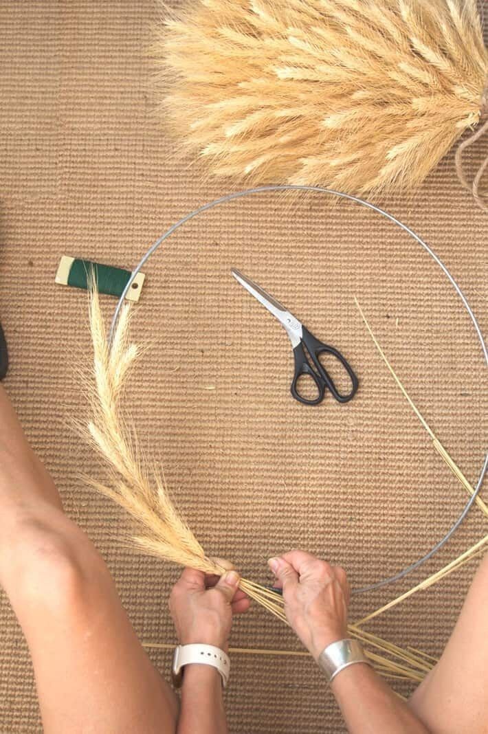 someone is working on some kind of crafting project with scissors and wheat stalks in front of them