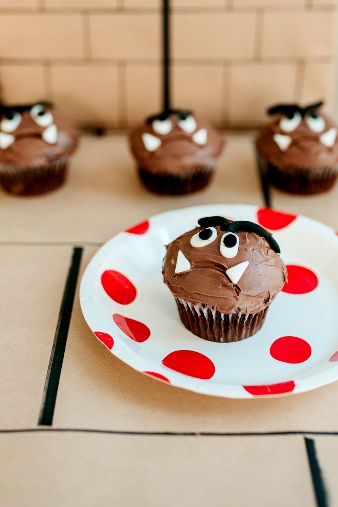 cupcakes with chocolate frosting and eyes are on a plate in front of other cupcakes