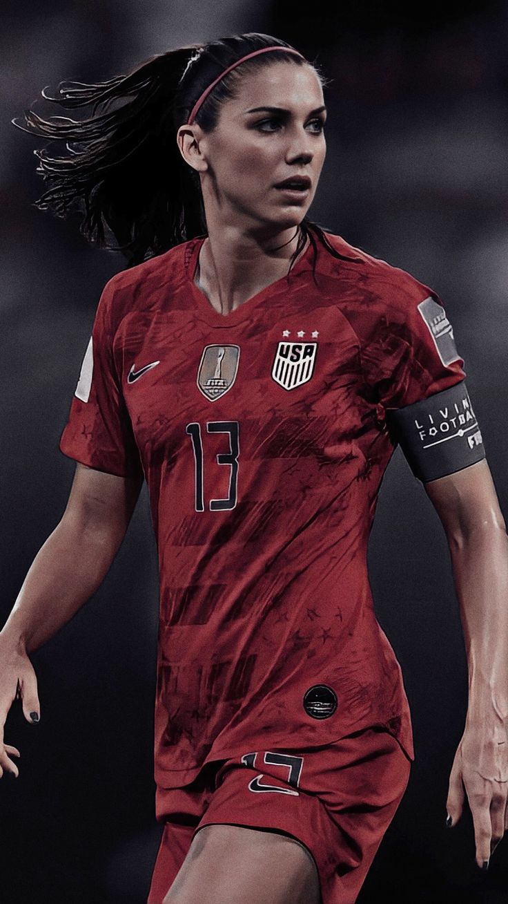 a female soccer player is running with the ball in her hand and she's wearing a red uniform