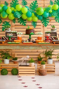 a table topped with lots of green balloons and potted plants next to a wall