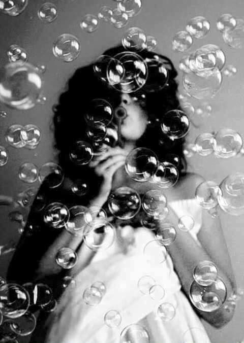 a woman is surrounded by bubbles in black and white