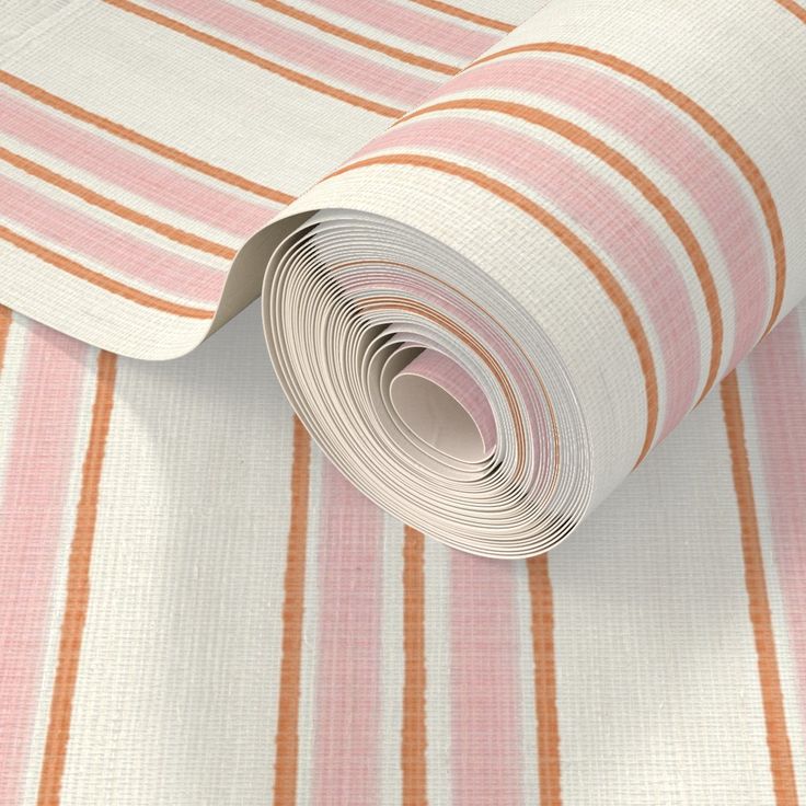 a roll of white and orange striped wallpaper on top of a pink table cloth