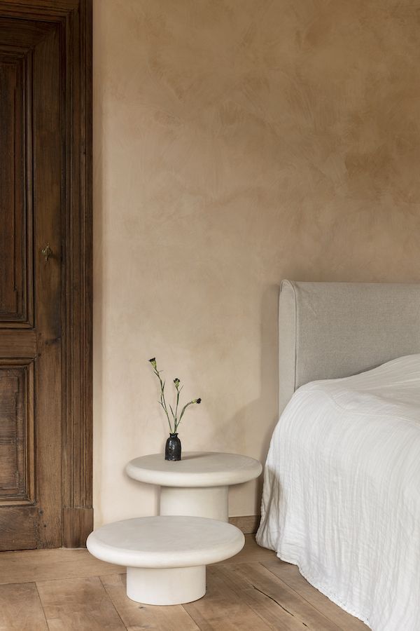 a bed sitting next to a white table on top of a hard wood floor in a bedroom