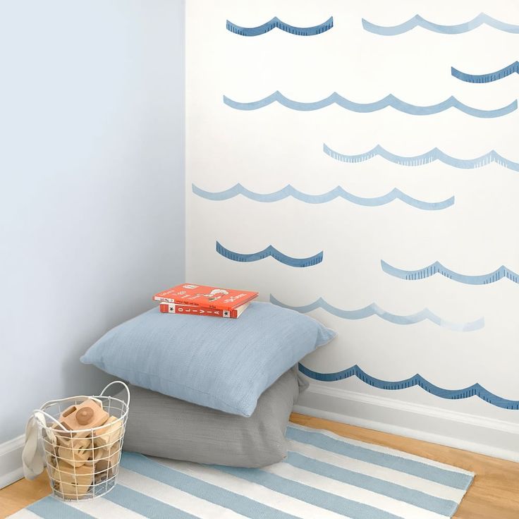 a blue and white wall with waves painted on it, next to a basket full of books