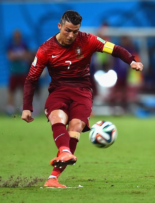 a man kicking a soccer ball on top of a field