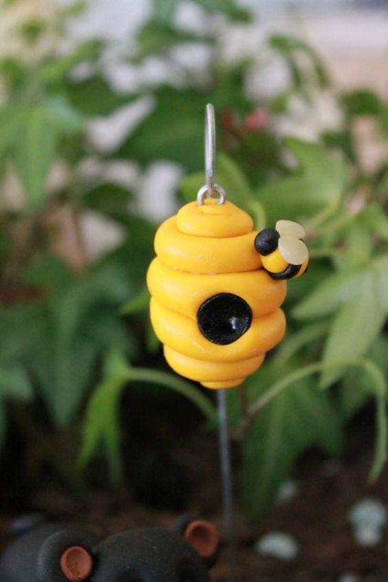 a yellow beehive hanging from a wire with two black eyes on it's face