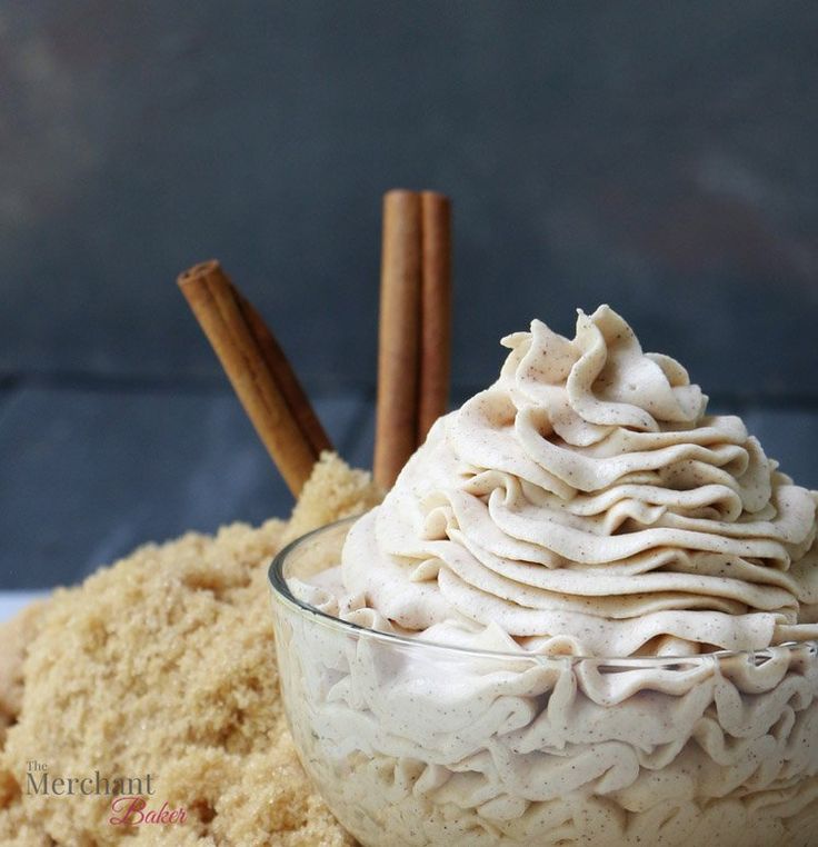 a bowl filled with whipped cream next to cinnamon sticks