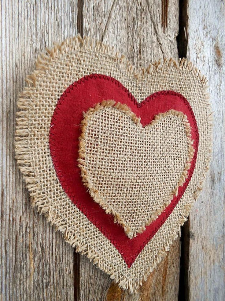 a heart shaped burlock hanging on a wooden wall with red trimmings