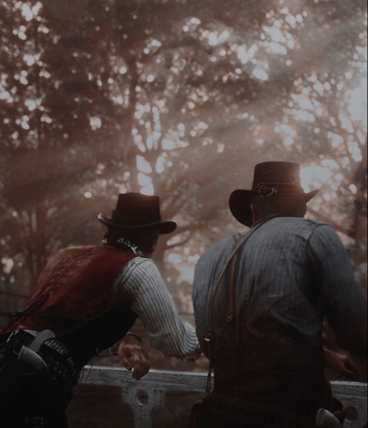 two men in hats and vests standing next to each other on a bridge with trees in the background