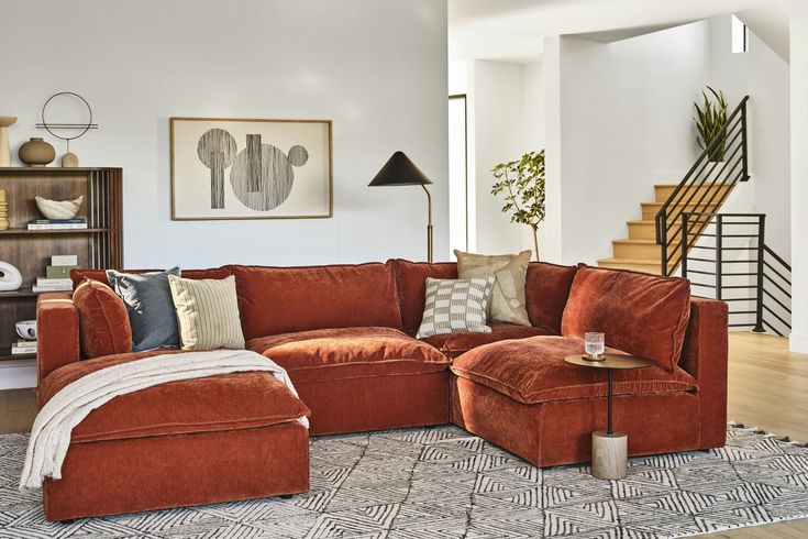 a living room with an orange couch and ottoman